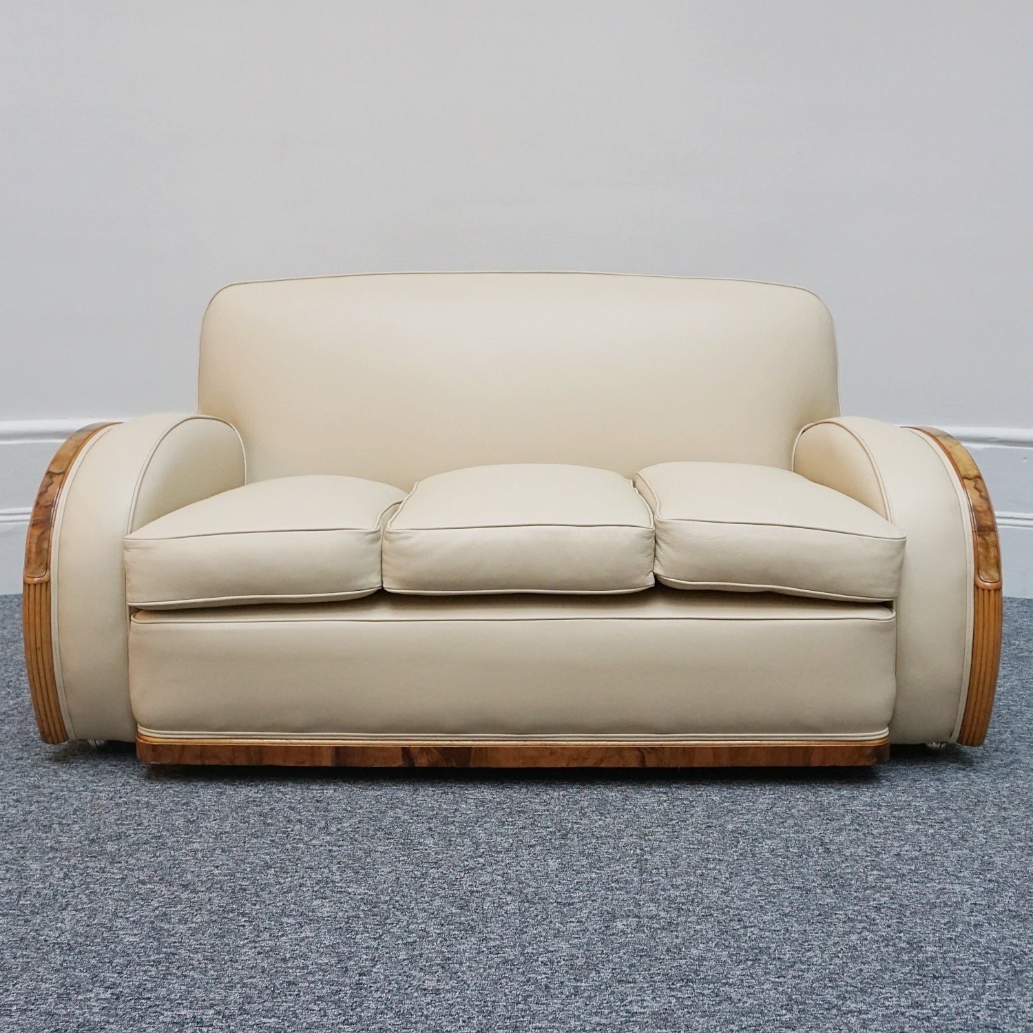 An Art Deco three piece tank Sofa by Heals of london. Made of Burr and solid walnut banding with reeded lower section, Upholstered in cream leather and contrasting faux suede