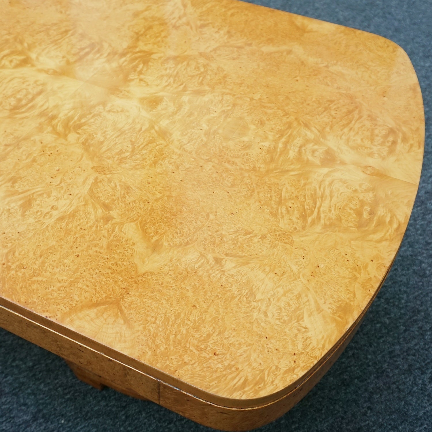 An art deco dining table with 6 chairs by Harry & Lou Epstein. The table top and cloud back armchairs are veneered in burr walnut. The chairs are upholstered in cream faux suede.
