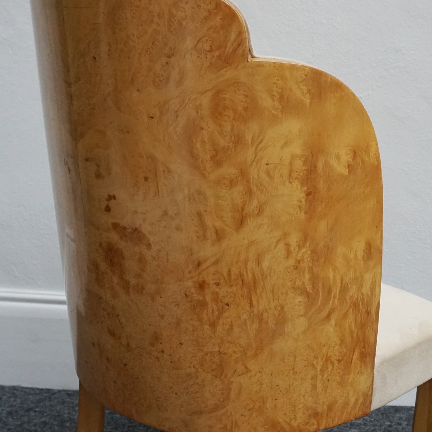 An art deco dining table with 6 chairs by Harry & Lou Epstein. The table top and cloud back armchairs are veneered in burr walnut. The chairs are upholstered in cream faux suede.