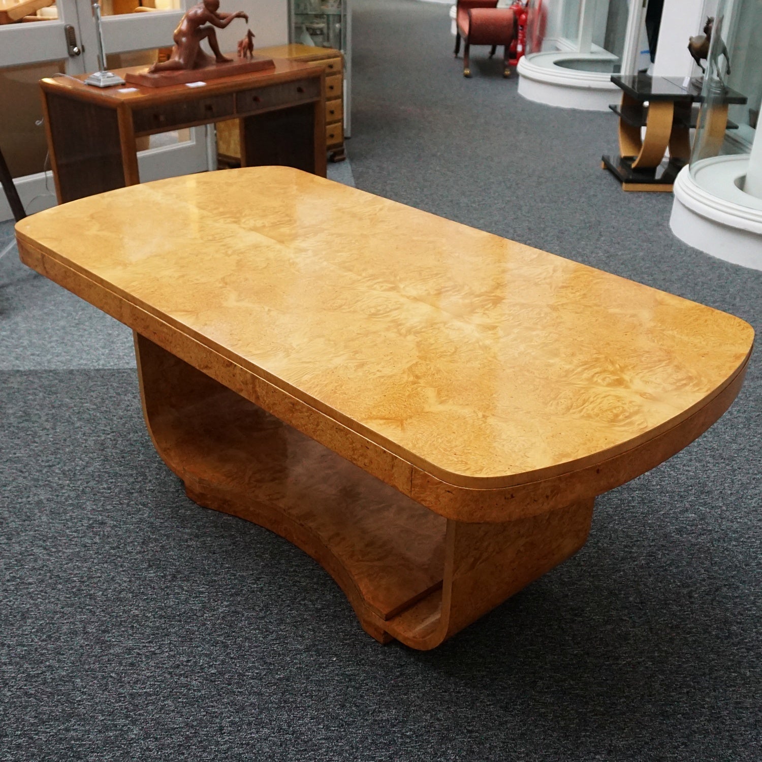 An art deco dining table with 6 chairs by Harry & Lou Epstein. The table top and cloud back armchairs are veneered in burr walnut. The chairs are upholstered in cream faux suede.