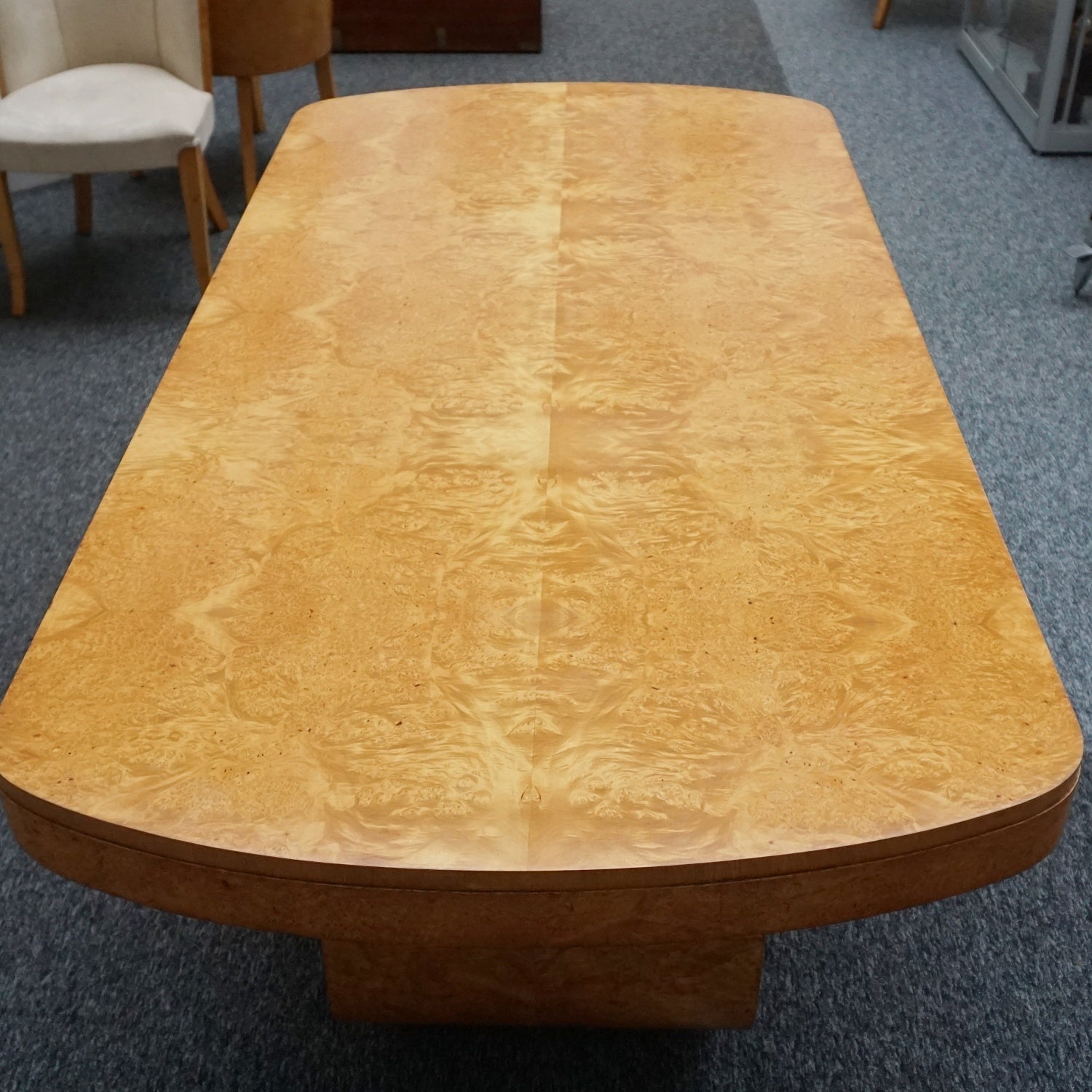 An art deco dining table with 6 chairs by Harry & Lou Epstein. The table top and cloud back armchairs are veneered in burr walnut. The chairs are upholstered in cream faux suede.