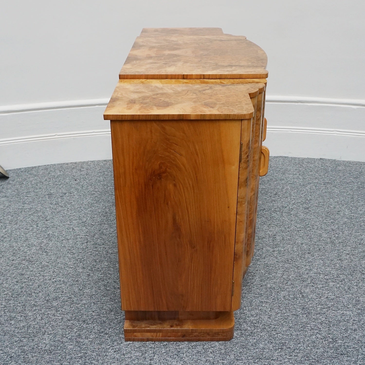 An Art Deco Sideboard by Harry & Lou Epstein with fluted sides set over a curved walnut base made of solid mahogany with burr walnut veneer