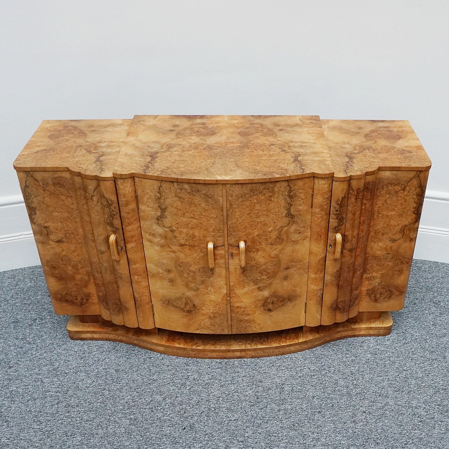 An Art Deco Sideboard by Harry & Lou Epstein with fluted sides set over a curved walnut base made of solid mahogany with burr walnut veneer