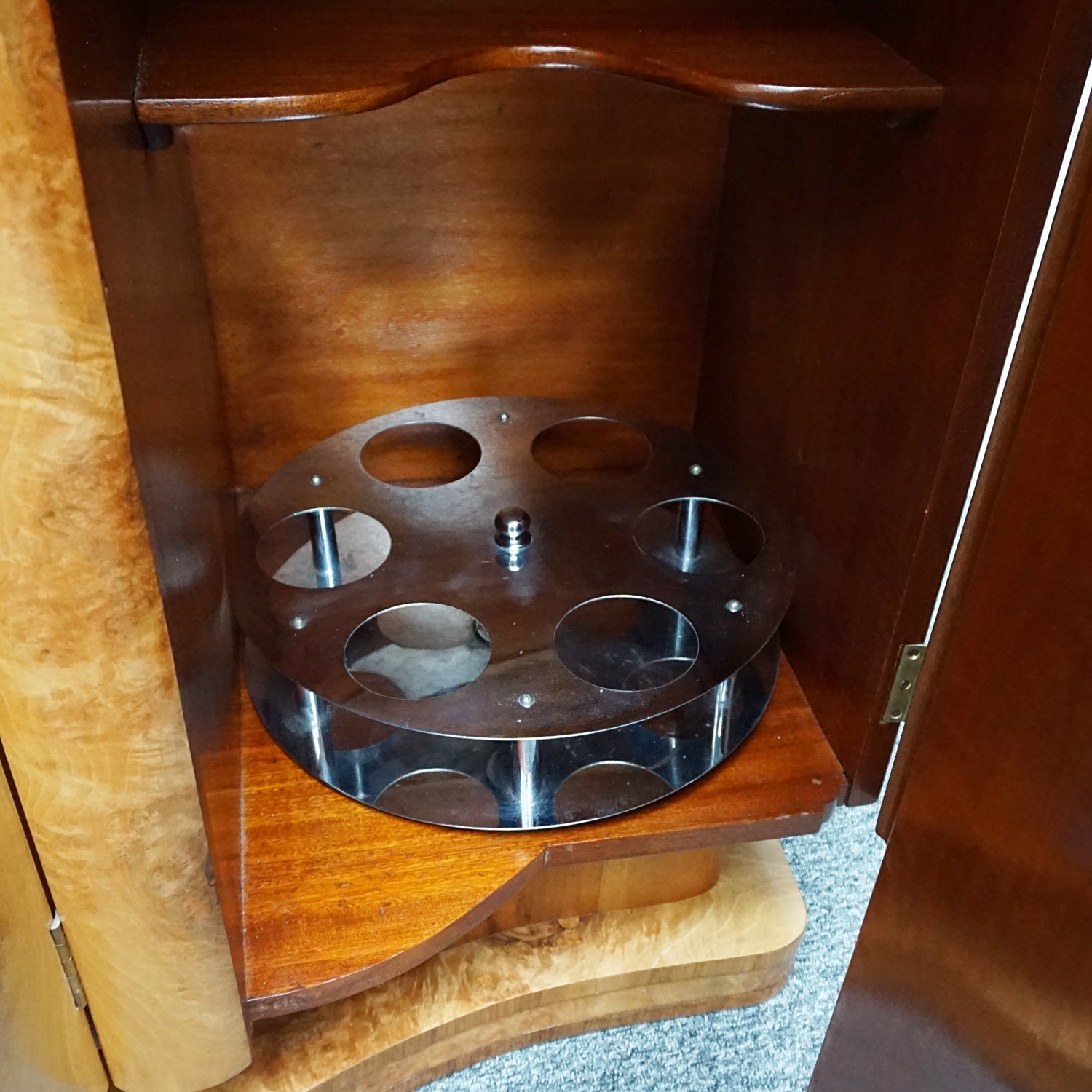 An Art Deco Sideboard by Harry & Lou Epstein with fluted sides set over a curved walnut base made of solid mahogany with burr walnut veneer. Left compartment contains a stainless steel rotating bottle holder with upper mahogany shelf