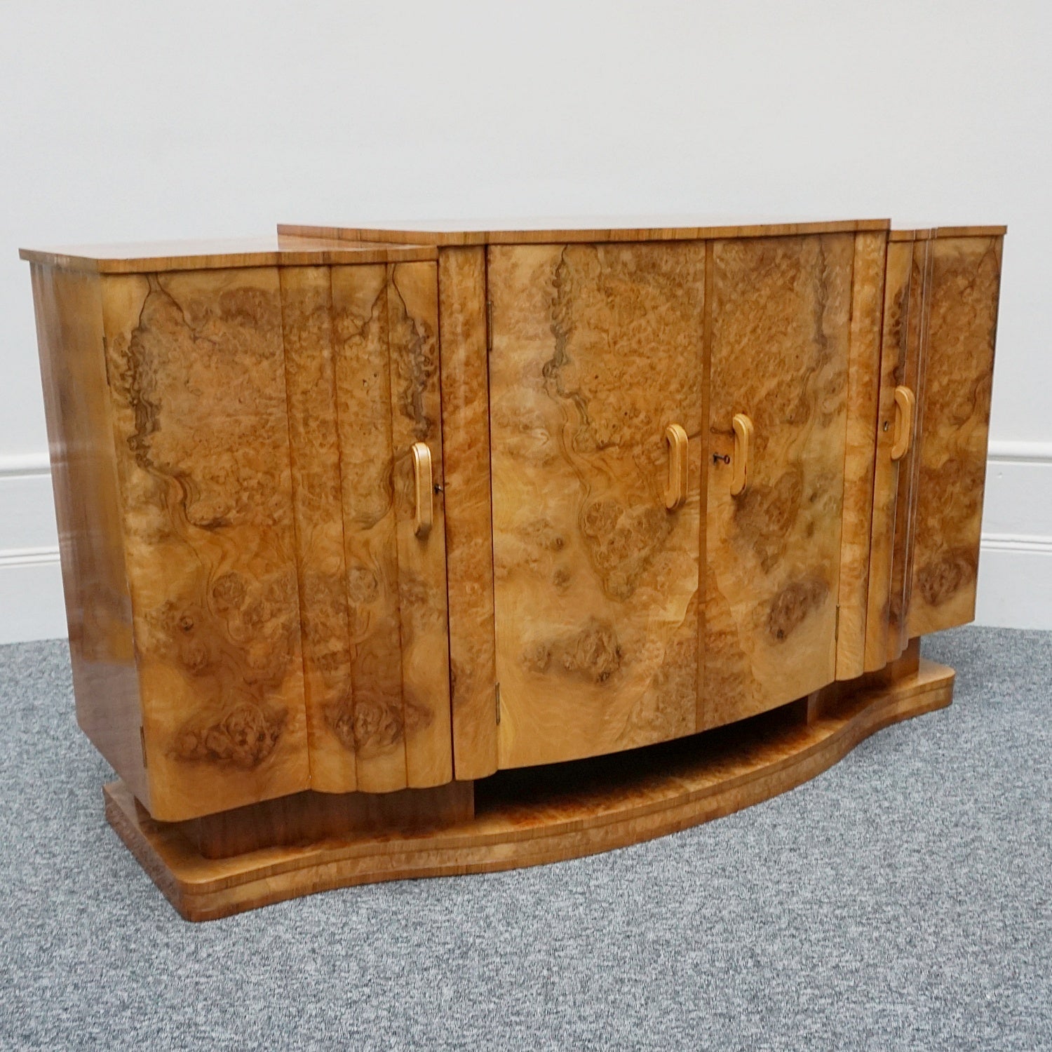 An Art Deco Sideboard by Harry & Lou Epstein with fluted sides set over a curved walnut base made of solid mahogany with burr walnut veneer