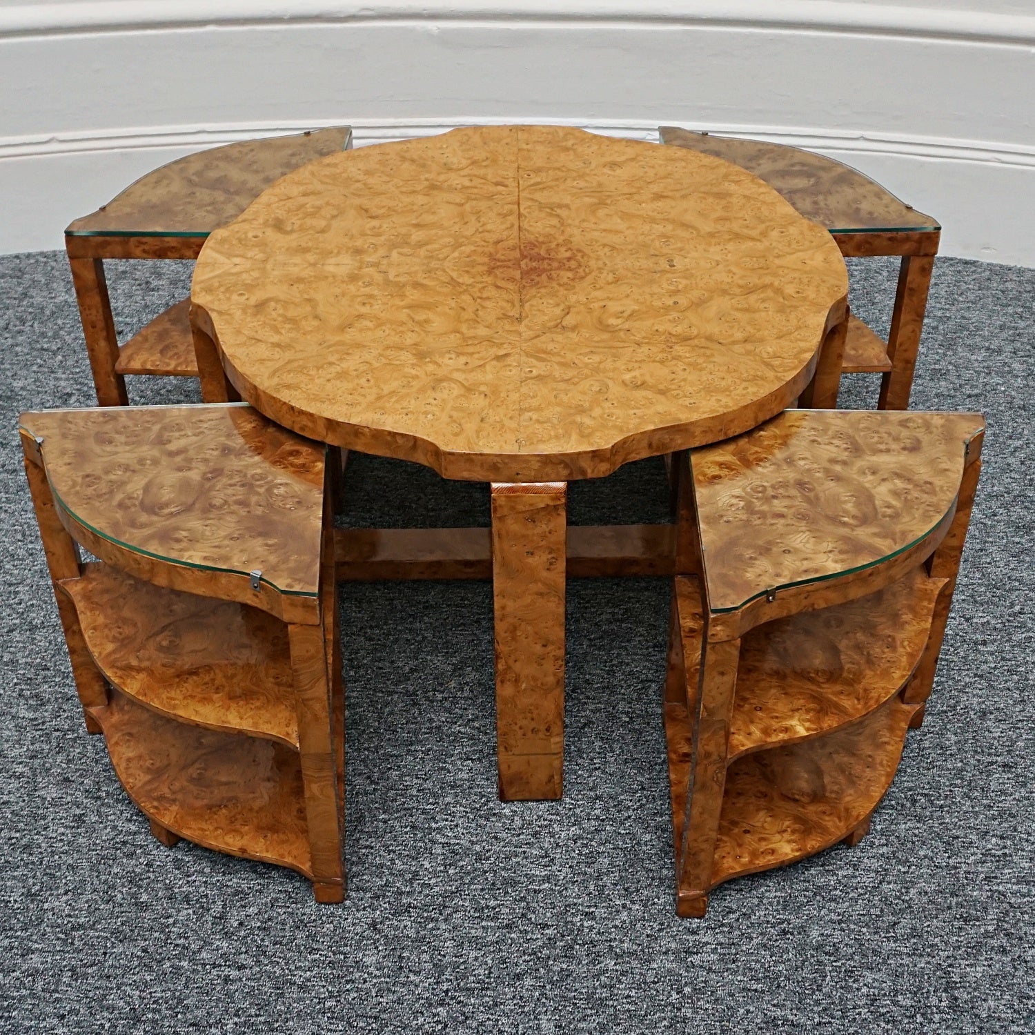 An Art Deco nest of tables by Harry & Lou Epstein Burr walnut veneered. Consisting of a central coffee table with four shelved pull out side tables. The tables have glass tops.
