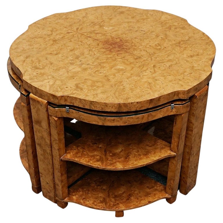 An Art Deco nest of tables by Harry & Lou Epstein Burr walnut veneered. Consisting of a central coffee table with four shelved pull out side tables. The tables have glass tops.