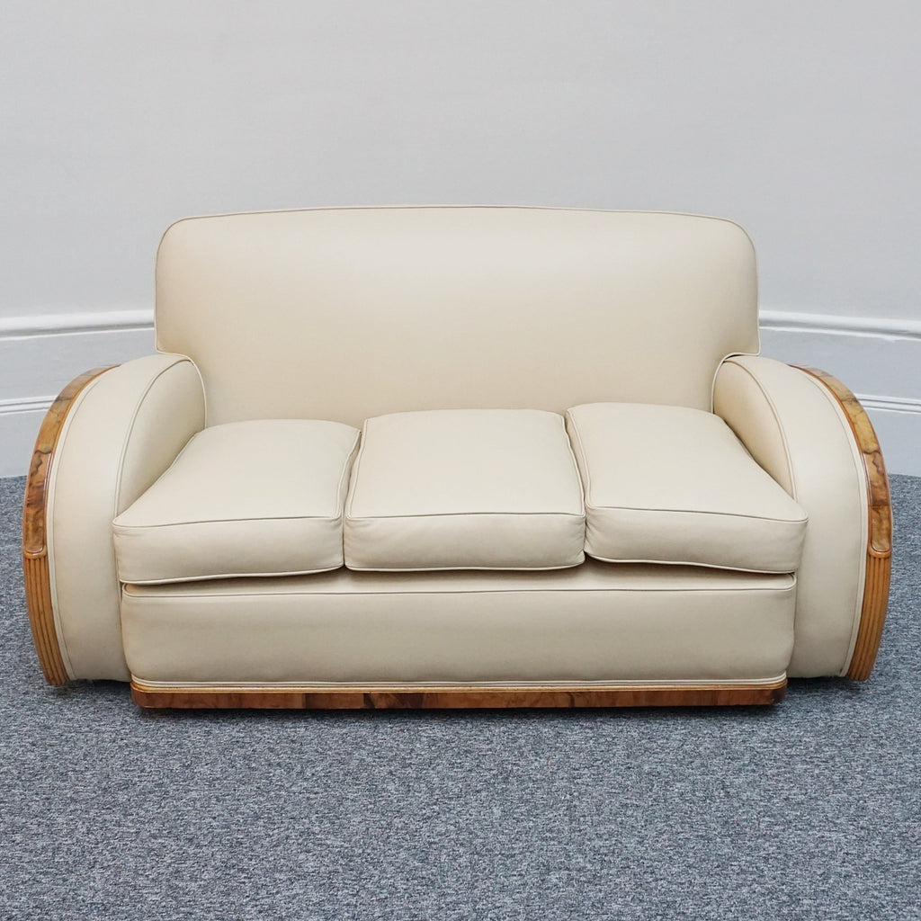An Art Deco three piece tank Sofa by Heals of london. Made of Burr and solid walnut banding with reeded lower section, Upholstered in cream leather and contrasting faux suede