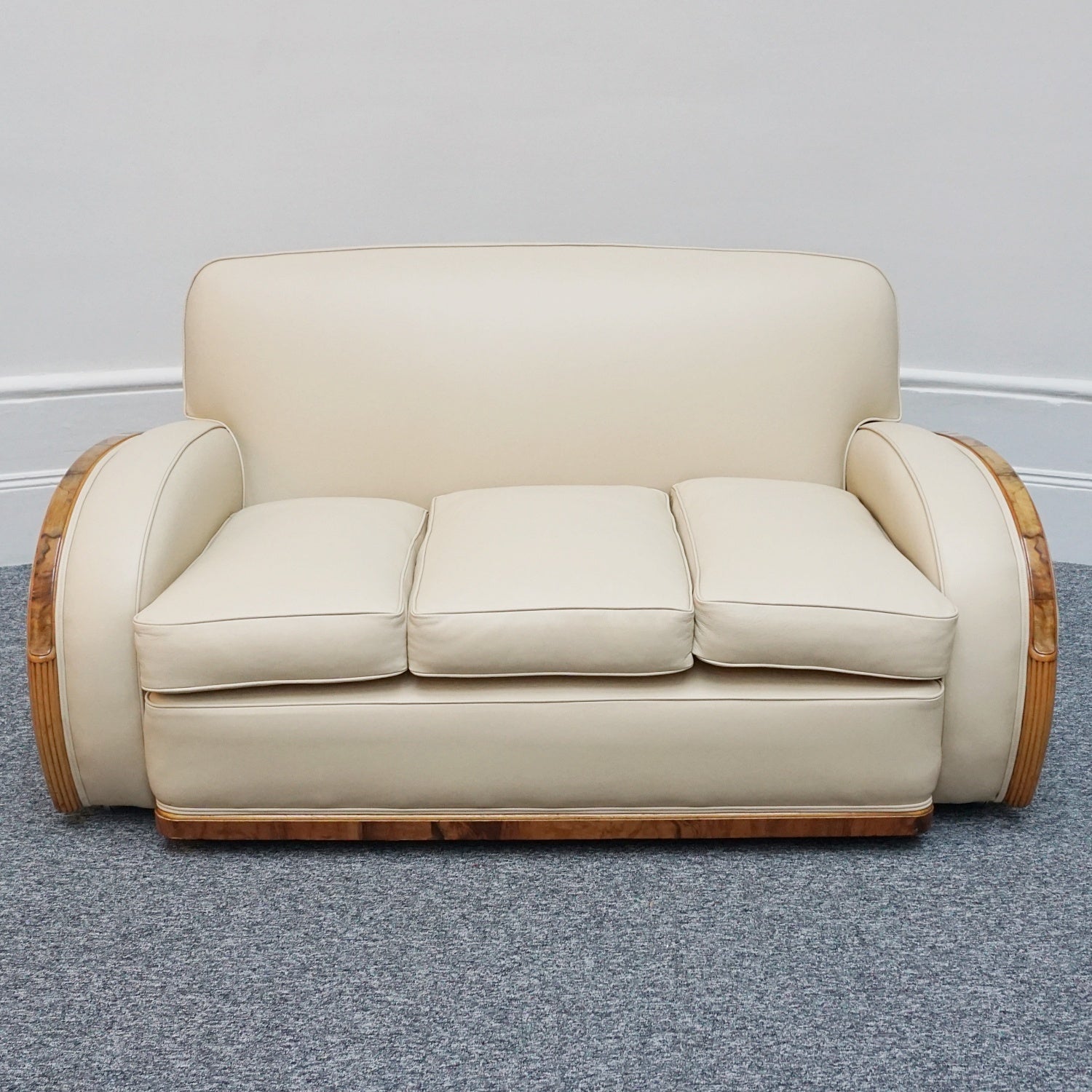 An Art Deco three piece tank Sofa by Heals of london. Made of Burr and solid walnut banding with reeded lower section, Upholstered in cream leather and contrasting faux suede