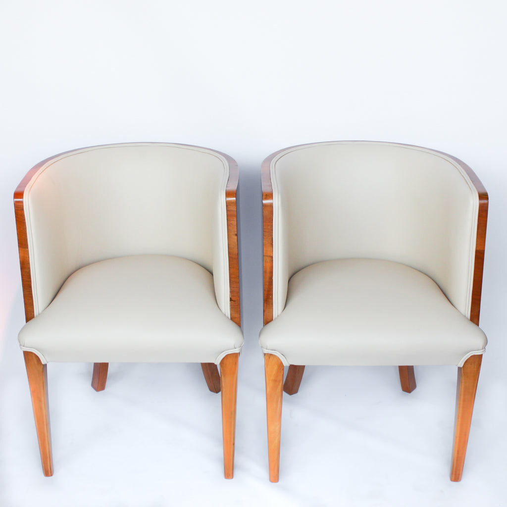 A pair of Art Deco tub chairs. Veneered walnut wrap frame. Solid satin birch legs. Upholstered in cream leather at Jeroen Markies.