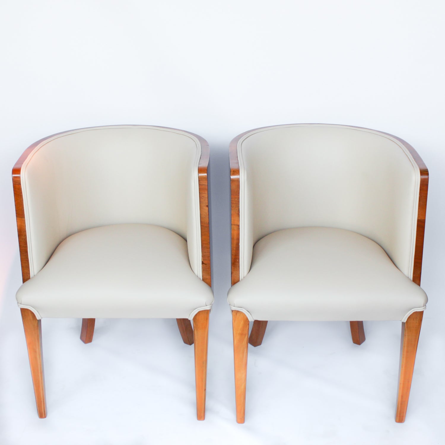 A pair of Art Deco tub chairs. Veneered walnut wrap frame. Solid satin birch legs. Upholstered in cream leather at Jeroen Markies.
