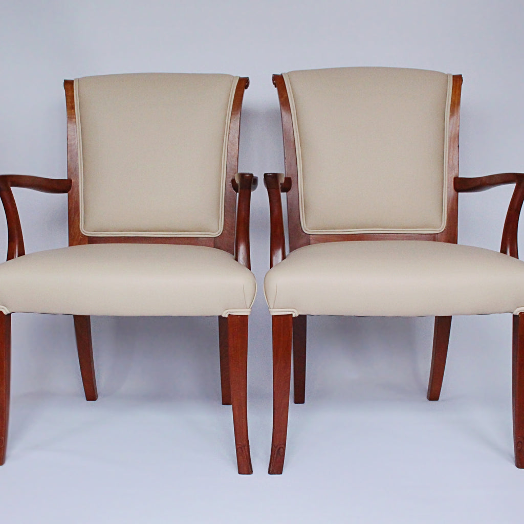 A pair of side chairs with walnut frames. Scrolled and carved detail to frames. Upholstered in cream leather. 