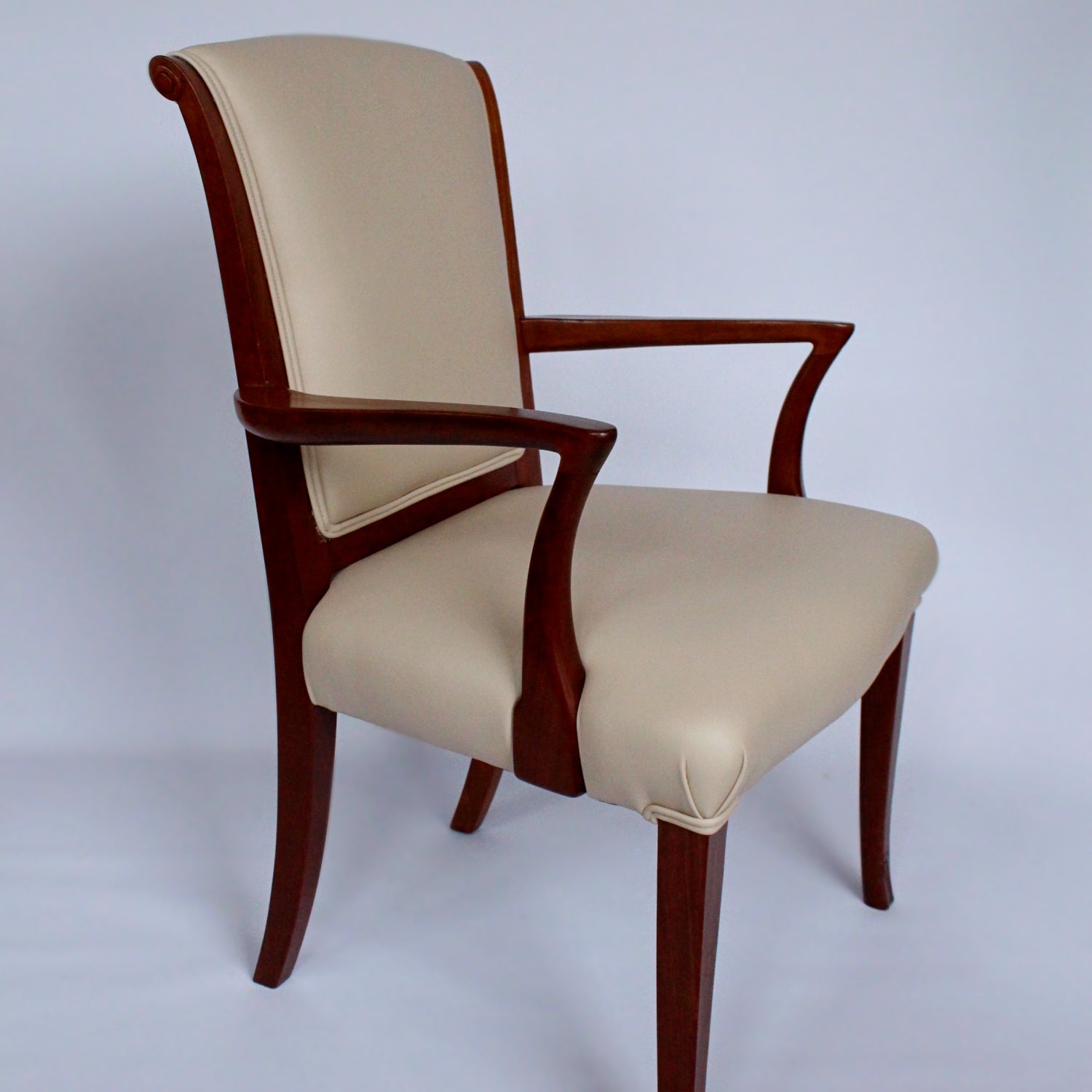 A pair of side chairs with walnut frames. Scrolled and carved detail to frames. Upholstered in cream leather. 