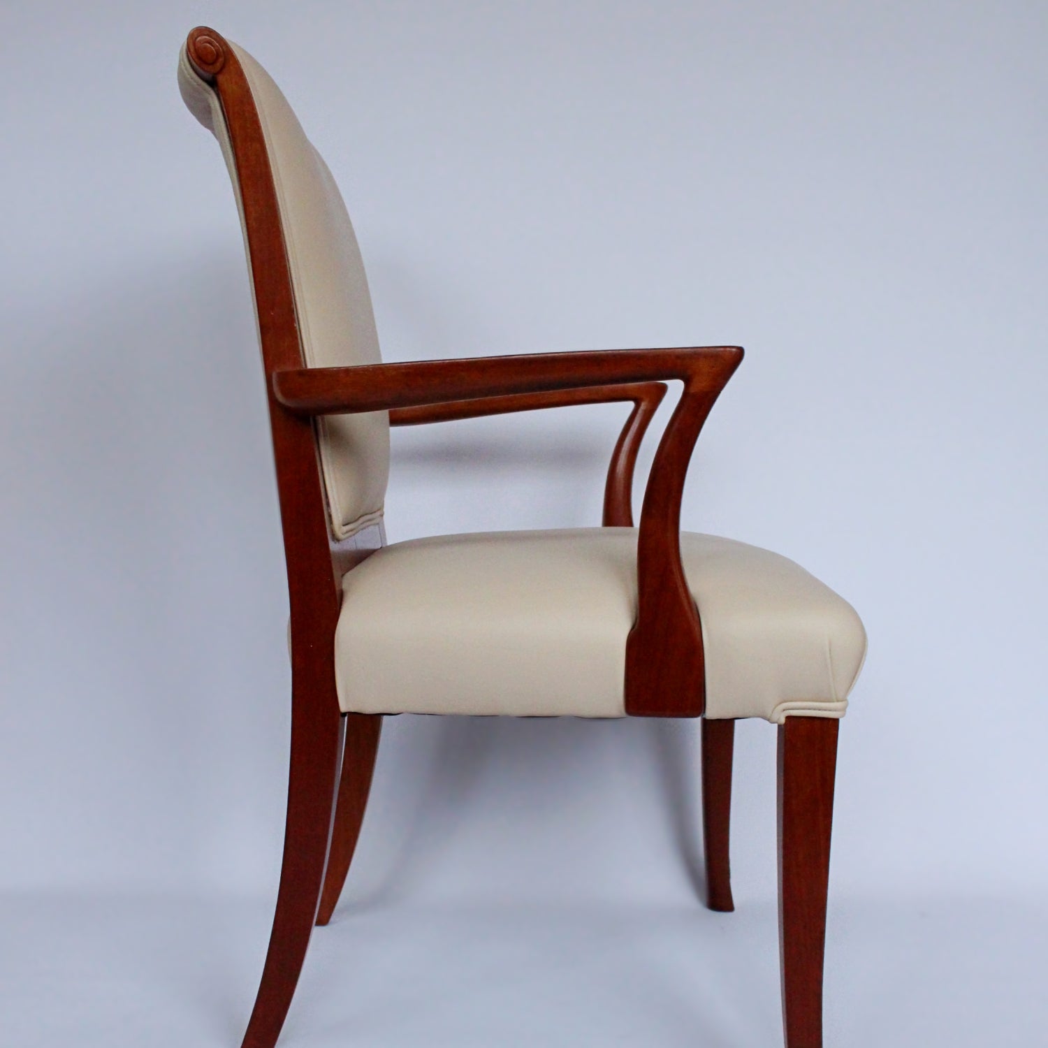 A pair of side chairs with walnut frames. Scrolled and carved detail to frames. Upholstered in cream leather. 