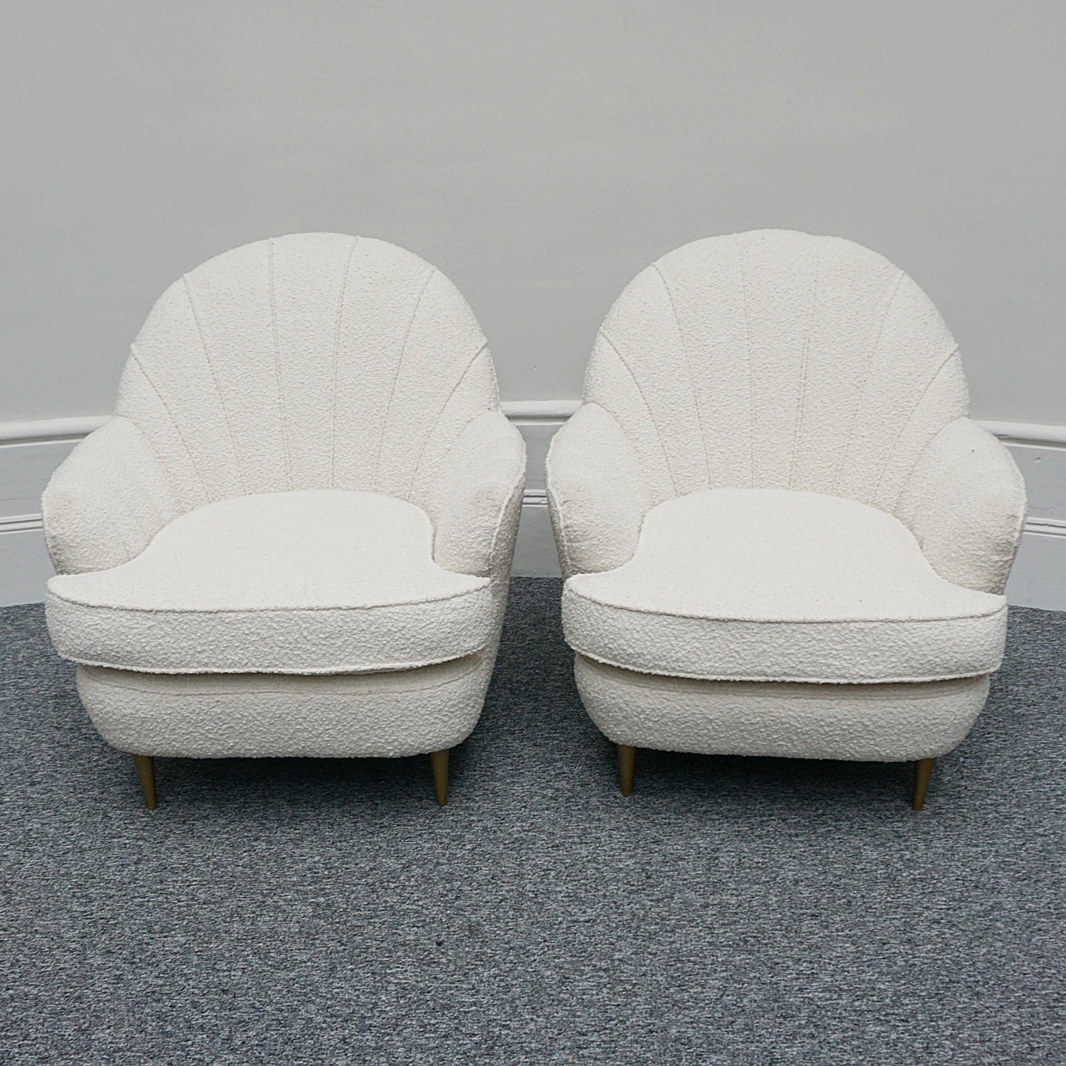 A pair of Mid Century lounge chairs upholstered in white Bouclé with metal and brass capped feet. Designed by Gigi Raddice for Minotti. 