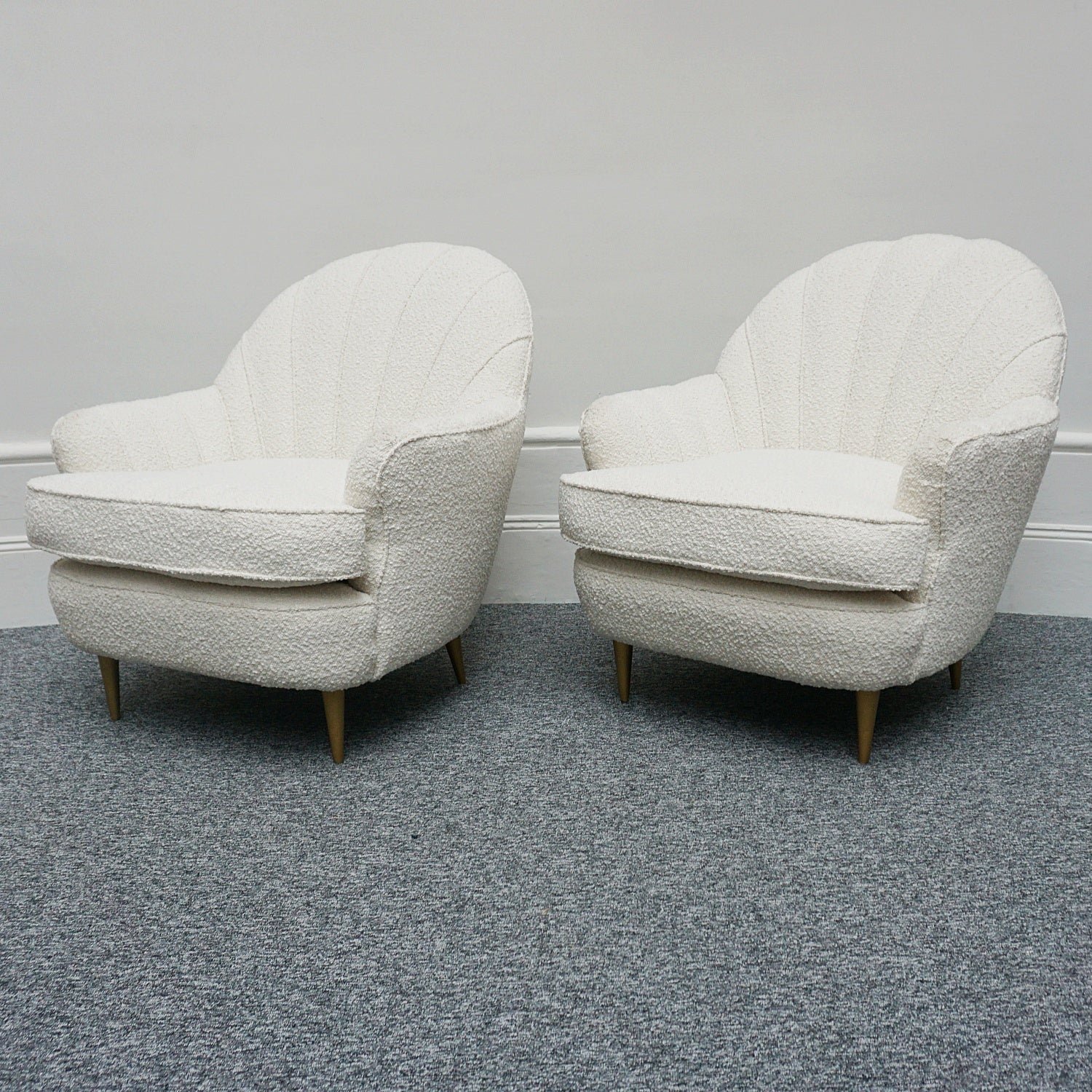 A pair of Mid Century lounge chairs upholstered in white Bouclé with metal and brass capped feet. Designed by Gigi Raddice for Minotti. 