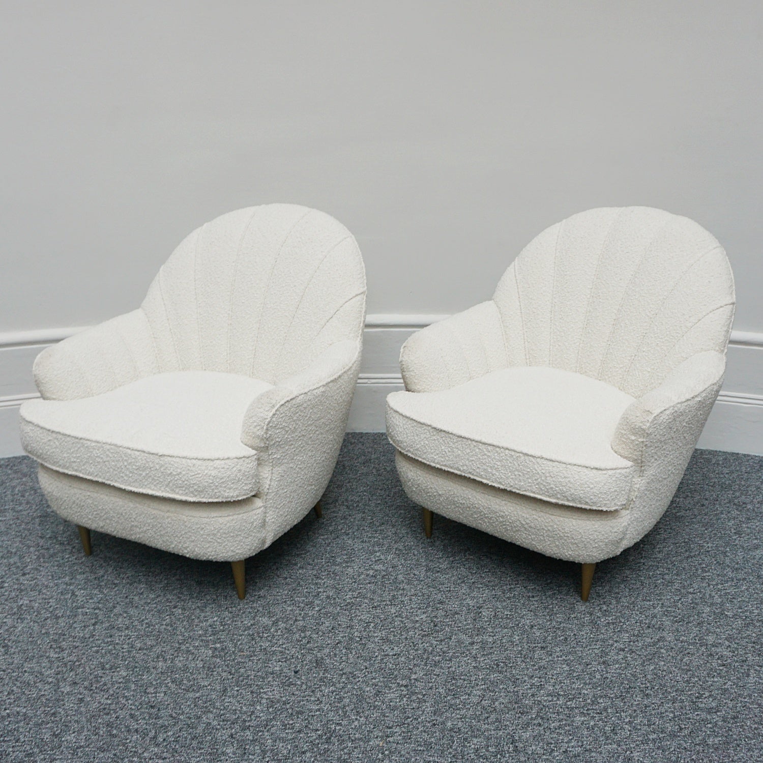 A pair of Mid Century lounge chairs upholstered in white Bouclé with metal and brass capped feet. Designed by Gigi Raddice for Minotti. 