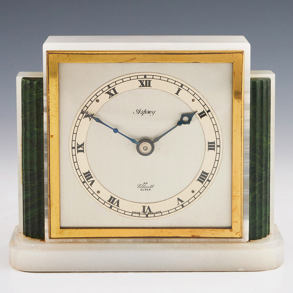An Art Deco mantel clock by Asprey made of white marbled onyx and green bevelled malachite with a square clock face featuring roman numerals framed with brass