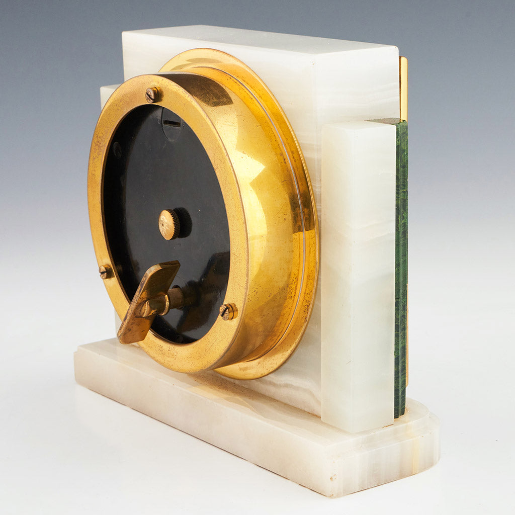 An Art Deco mantel clock by Asprey made of white marbled onyx and green bevelled malachite with a square clock face featuring roman numerals framed with brass