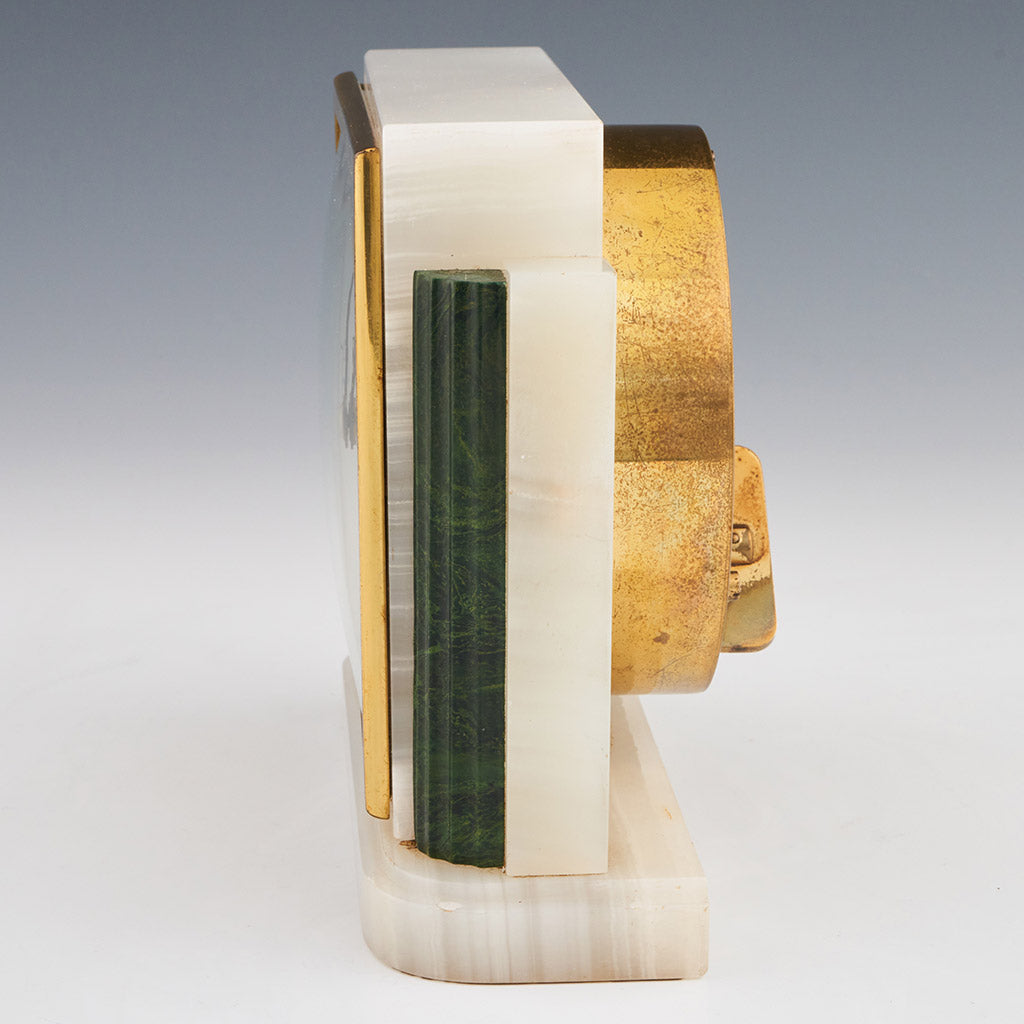 An Art Deco mantel clock by Asprey made of white marbled onyx and green bevelled malachite with a square clock face featuring roman numerals framed with brass