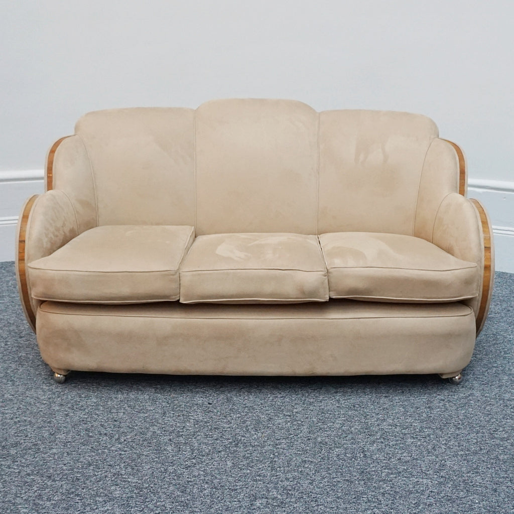 An Art Deco cloud back sofa by Harry & Lou Epstein with figured walnut banding to the arms and upholstered in cream faux suede