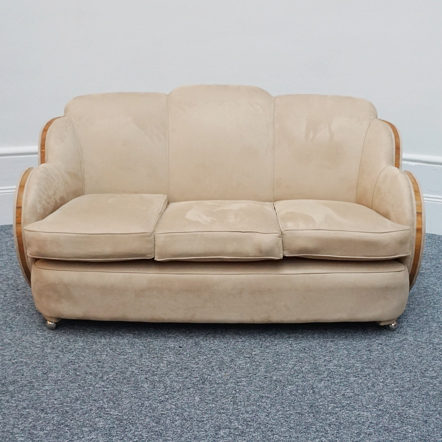 An Art Deco cloud back sofa by Harry & Lou Epstein with figured walnut banding to the arms and upholstered in cream faux suede