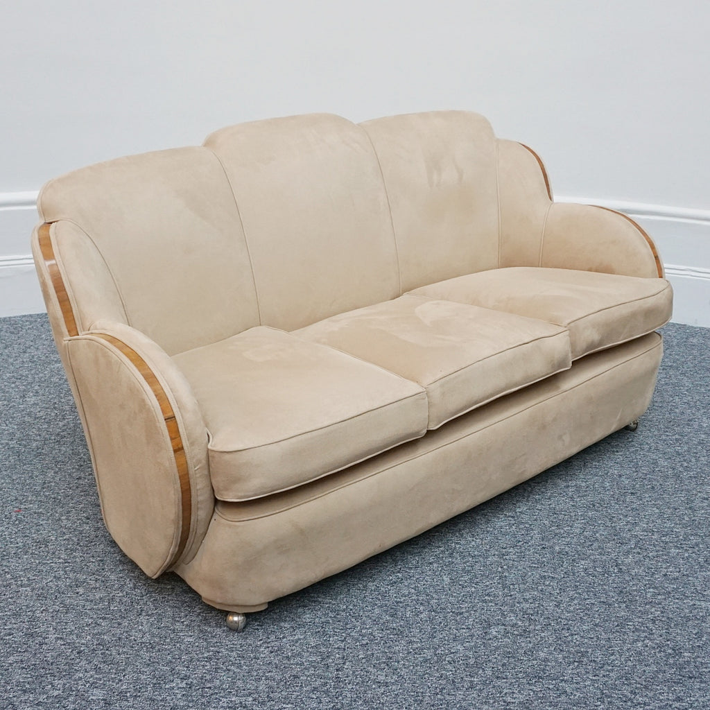 An Art Deco cloud back sofa by Harry & Lou Epstein with figured walnut banding to the arms and upholstered in cream faux suede