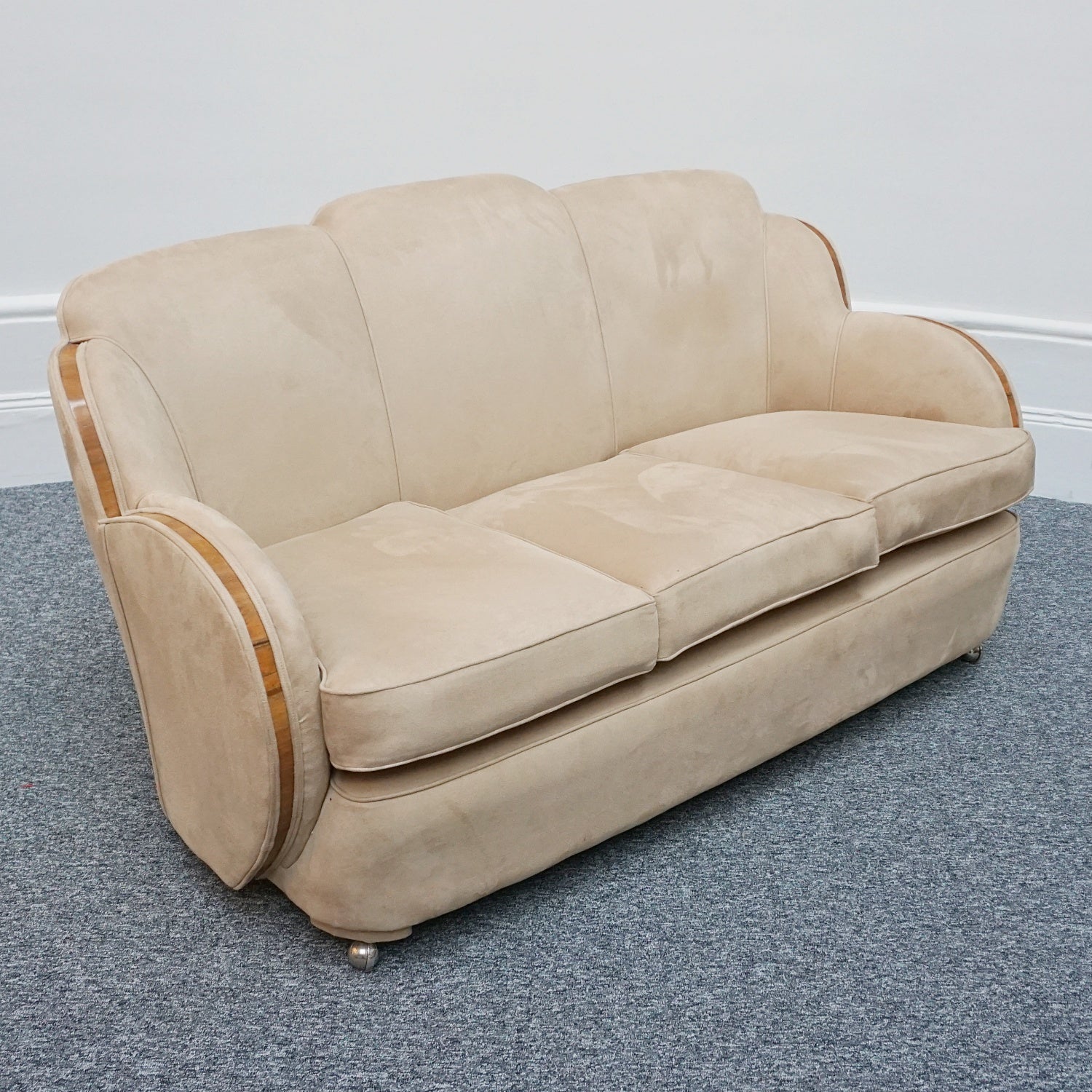 An Art Deco cloud back sofa by Harry & Lou Epstein with figured walnut banding to the arms and upholstered in cream faux suede