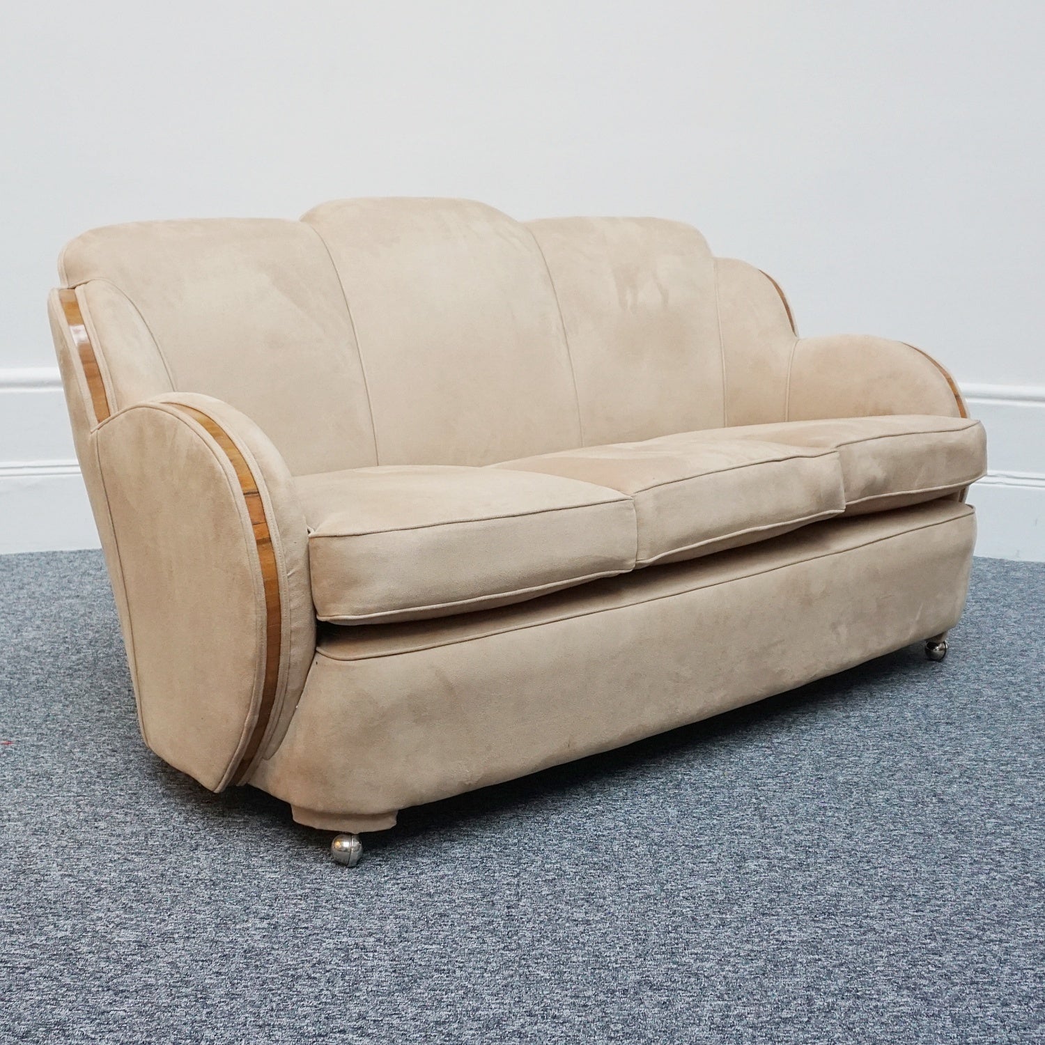 An Art Deco cloud back sofa by Harry & Lou Epstein with figured walnut banding to the arms and upholstered in cream faux suede
