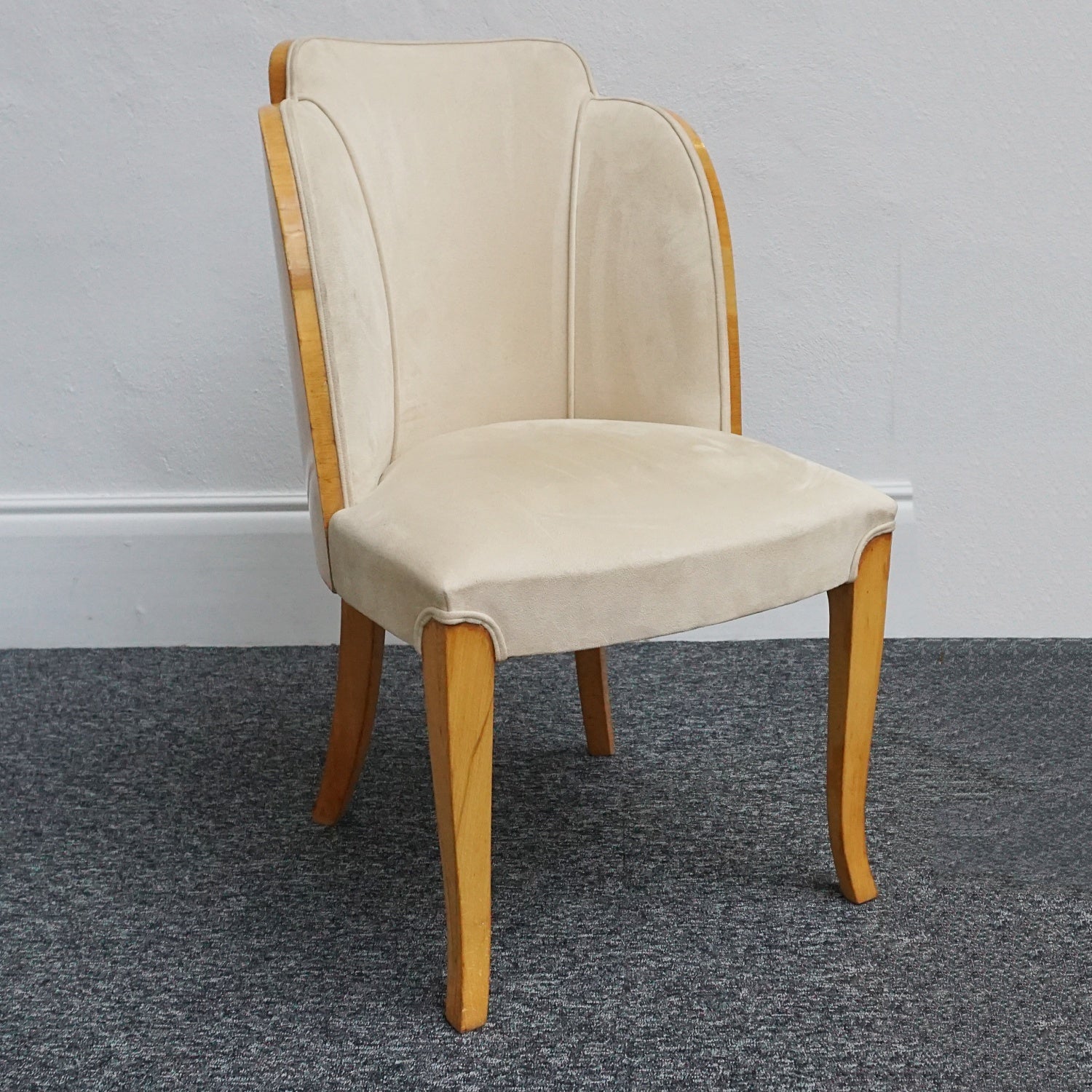 An art deco dining table with 6 chairs by Harry & Lou Epstein. The table top and cloud back armchairs are veneered in burr walnut. The chairs are upholstered in cream faux suede. 