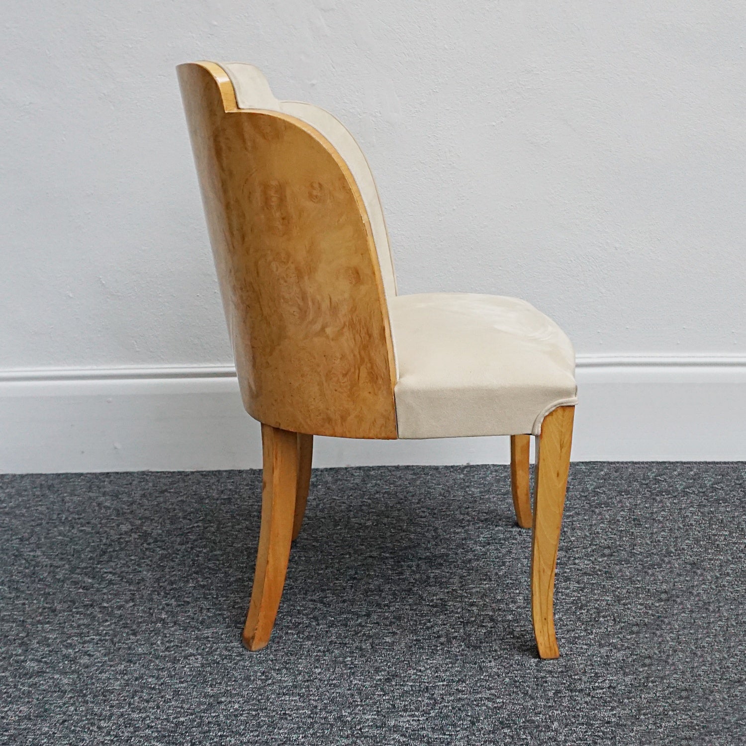 An art deco dining table with 6 chairs by Harry & Lou Epstein. The table top and cloud back armchairs are veneered in burr walnut. The chairs are upholstered in cream faux suede. 