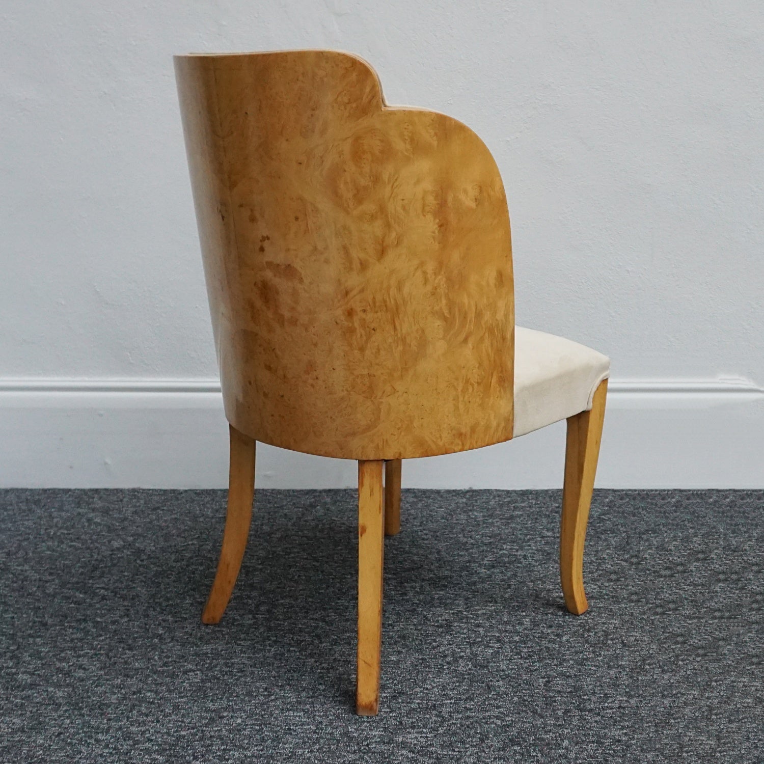 An art deco dining table with 6 chairs by Harry & Lou Epstein. The table top and cloud back armchairs are veneered in burr walnut. The chairs are upholstered in cream faux suede. 