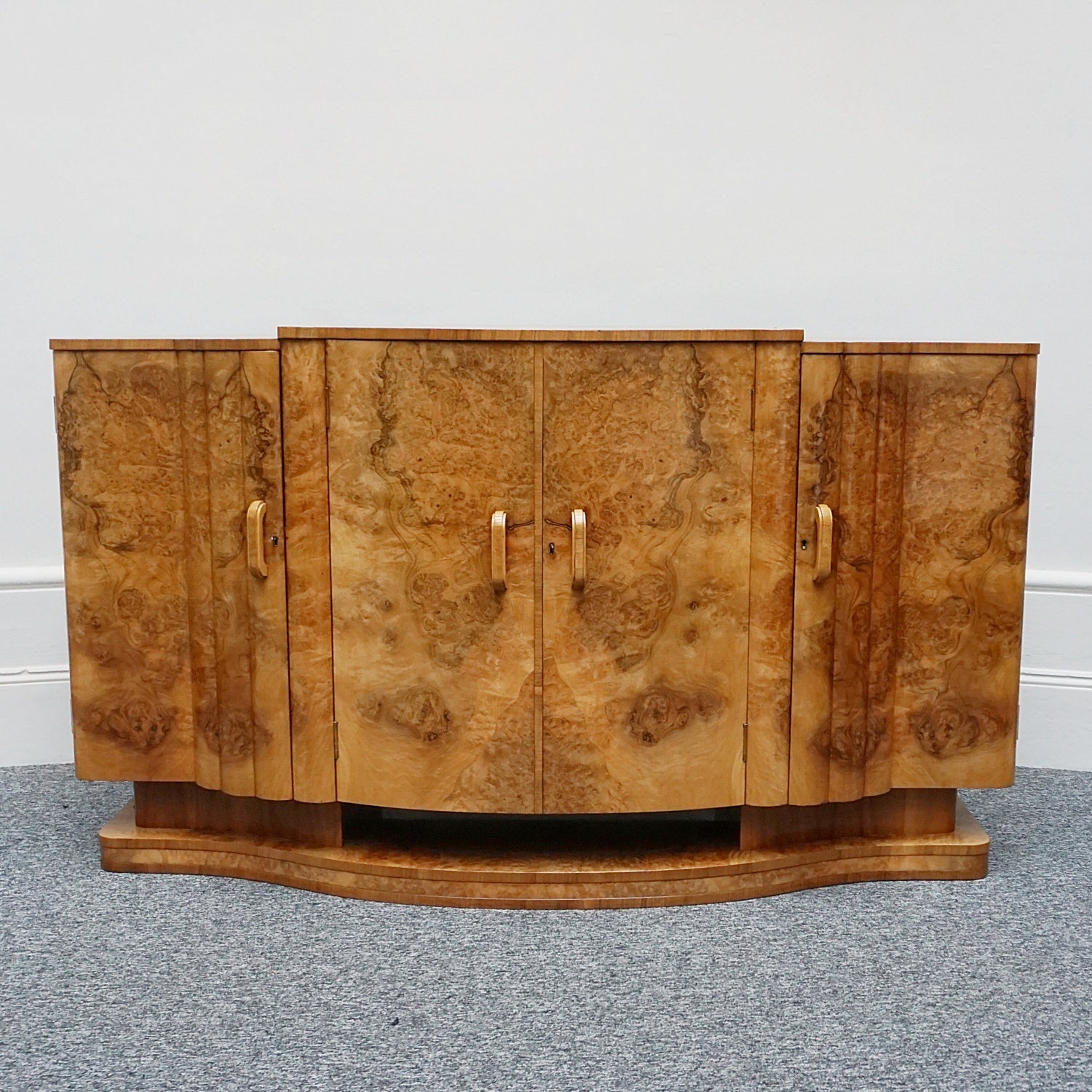 An Art Deco Sideboard by Harry & Lou Epstein with fluted sides set over a curved walnut base made of solid mahogany with burr walnut veneer
