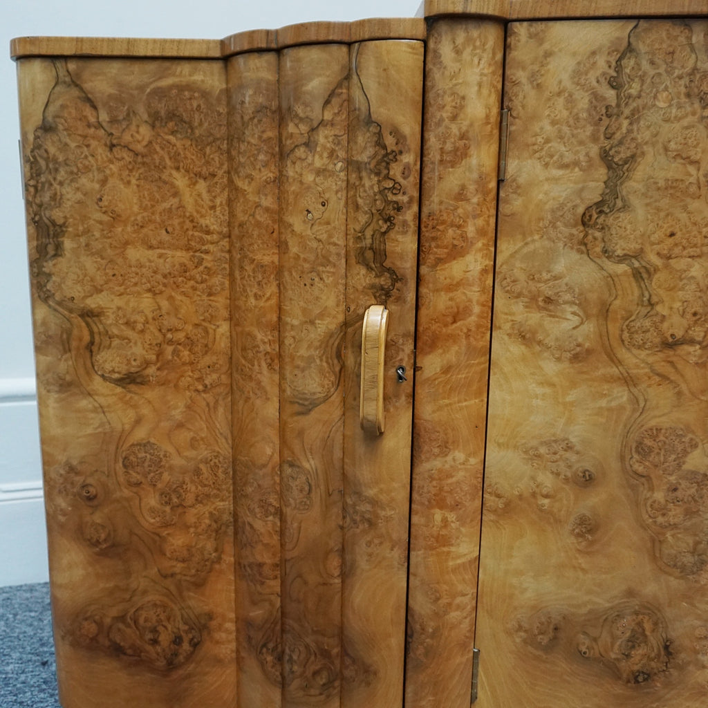 An Art Deco Sideboard by Harry & Lou Epstein with fluted sides set over a curved walnut base made of solid mahogany with burr walnut veneer