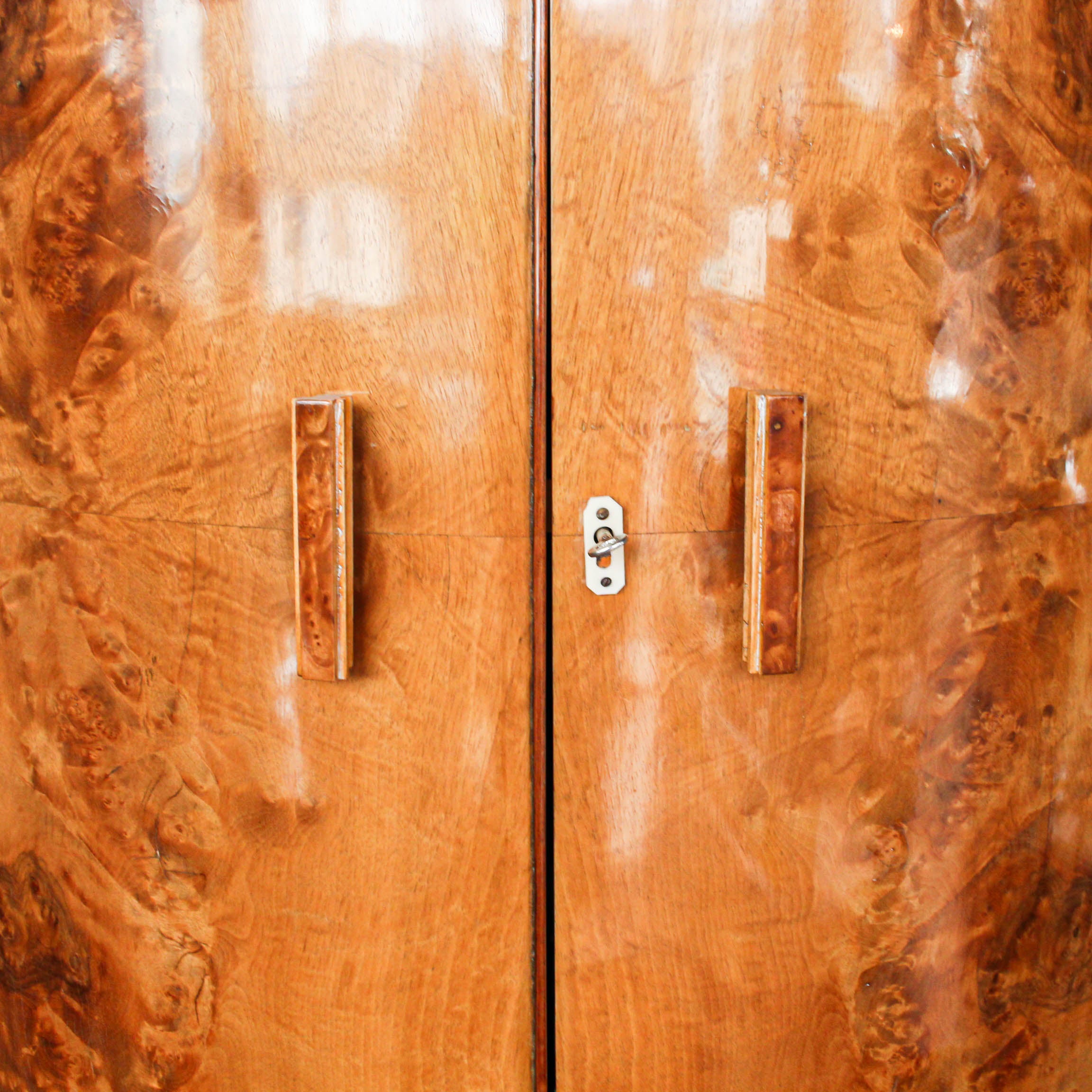 An Art Deco, demi-lune cocktail cabinet attributed to Harry & Lou Epstein. Mirrored, lit interior to top with glass shelves and mirrored slide tray. Lower, shelved cabinet with bottle holders. Burr walnut veneer at Jeroen Markies.
