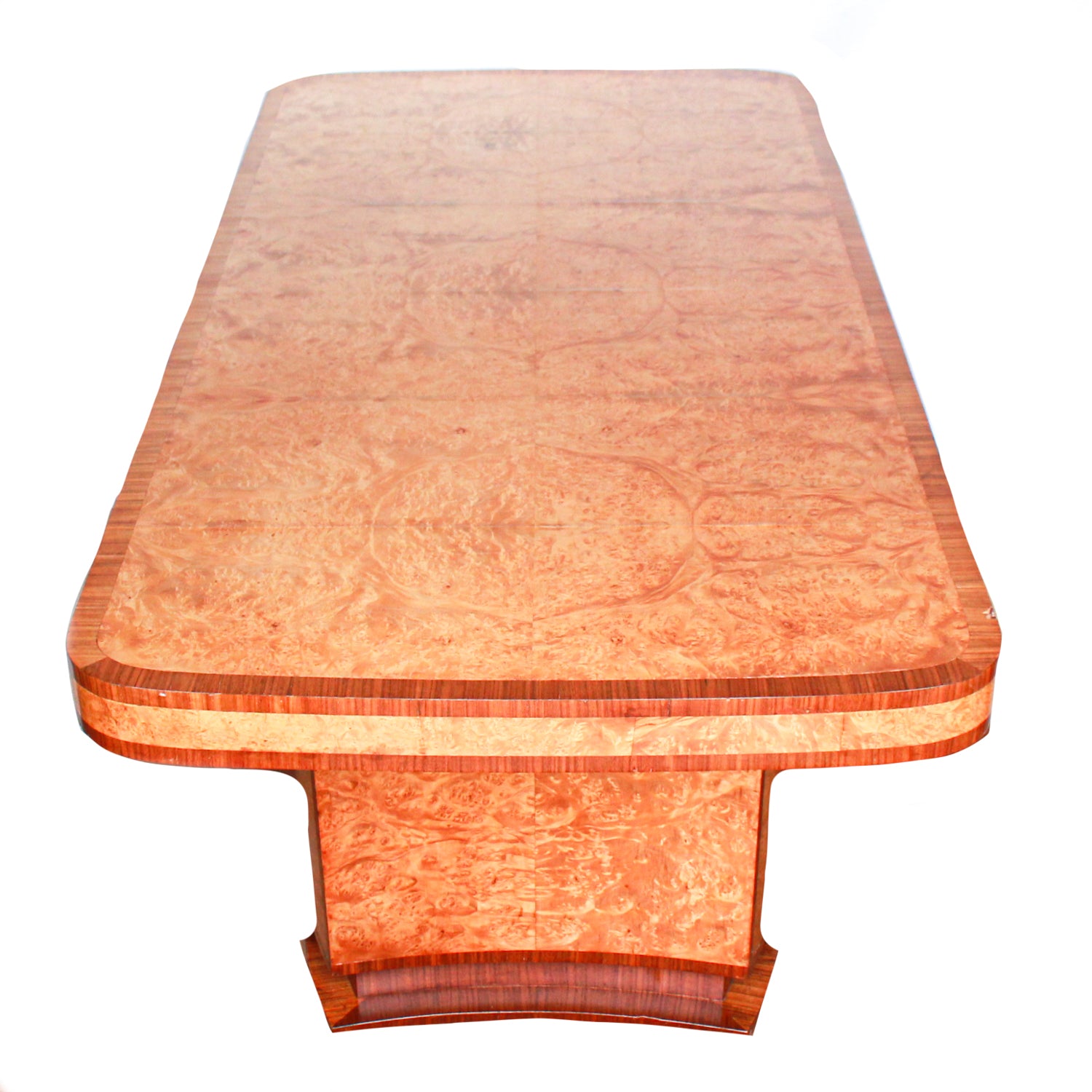 An Art Deco dining table and six chairs. Serpentine edged, burr walnut table set over pedestal legs in straight grain walnut with burr walnut reeded detail. Cloud back chairs upholstered in cream leather.