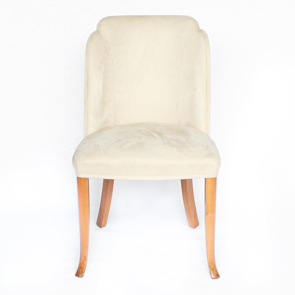 An Art Deco dining table and six chairs. Serpentine edged, burr walnut table set over pedestal legs in straight grain walnut with burr walnut reeded detail. Cloud back chairs upholstered in cream leather.