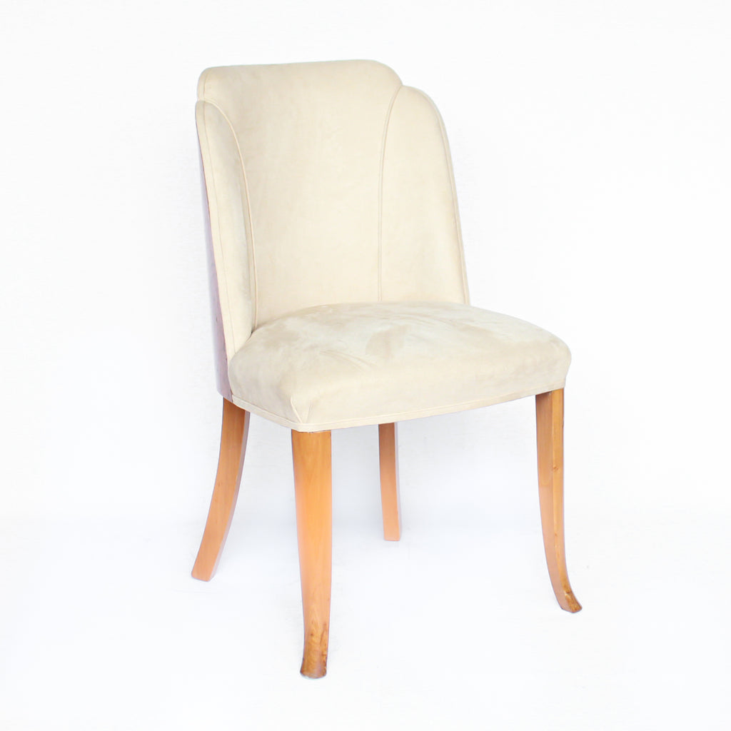 An Art Deco dining table and six chairs. Serpentine edged, burr walnut table set over pedestal legs in straight grain walnut with burr walnut reeded detail. Cloud back chairs upholstered in cream leather.