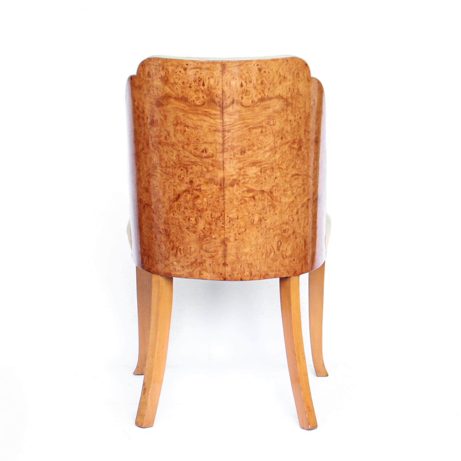 An Art Deco dining table and six chairs. Serpentine edged, burr walnut table set over pedestal legs in straight grain walnut with burr walnut reeded detail. Cloud back chairs upholstered in cream leather.