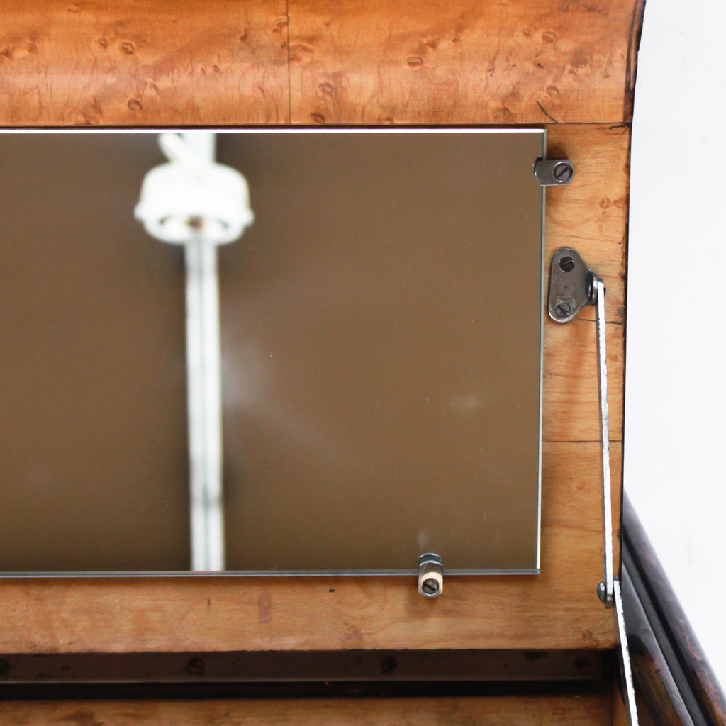 An Art Deco serving/drinks trolley with mirrored top. Double ice-box to one side with drinks cabinet to opposite side, including lower compartment for glasses. Macassar ebony throughout with walnut banding. Original chrome handle and rolling castors.