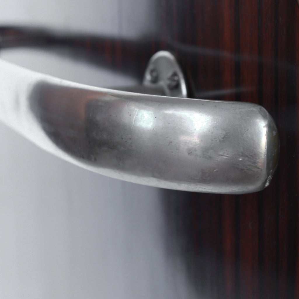 An Art Deco serving/drinks trolley with mirrored top. Double ice-box to one side with drinks cabinet to opposite side, including lower compartment for glasses. Macassar ebony throughout with walnut banding. Original chrome handle and rolling castors.