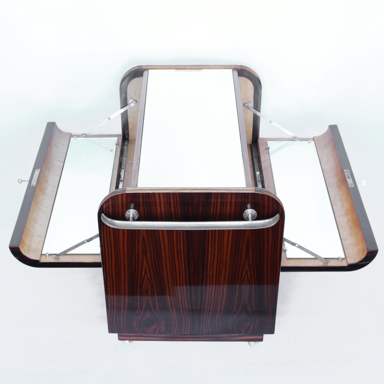 An Art Deco serving/drinks trolley with mirrored top. Double ice-box to one side with drinks cabinet to opposite side, including lower compartment for glasses. Macassar ebony throughout with walnut banding. Original chrome handle and rolling castors.