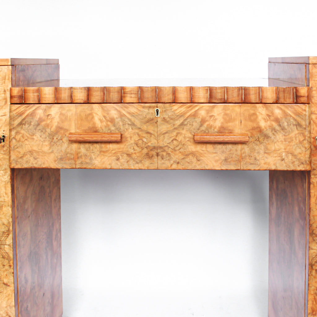 An Art Deco console sideboard by Hille. Burr walnut veneer throughout. Scallop-edged detail to front with integral drawer. Shelved cabinets to either side.