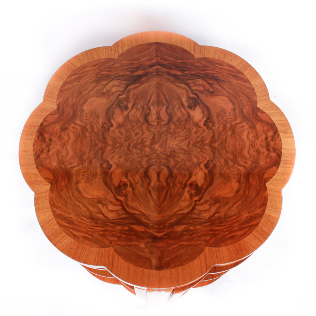 An Art Deco nest of tables in figured and straight grain walnut veneer. Main table with shaped edging set over cross footed base. Four shelved, integral side tables.