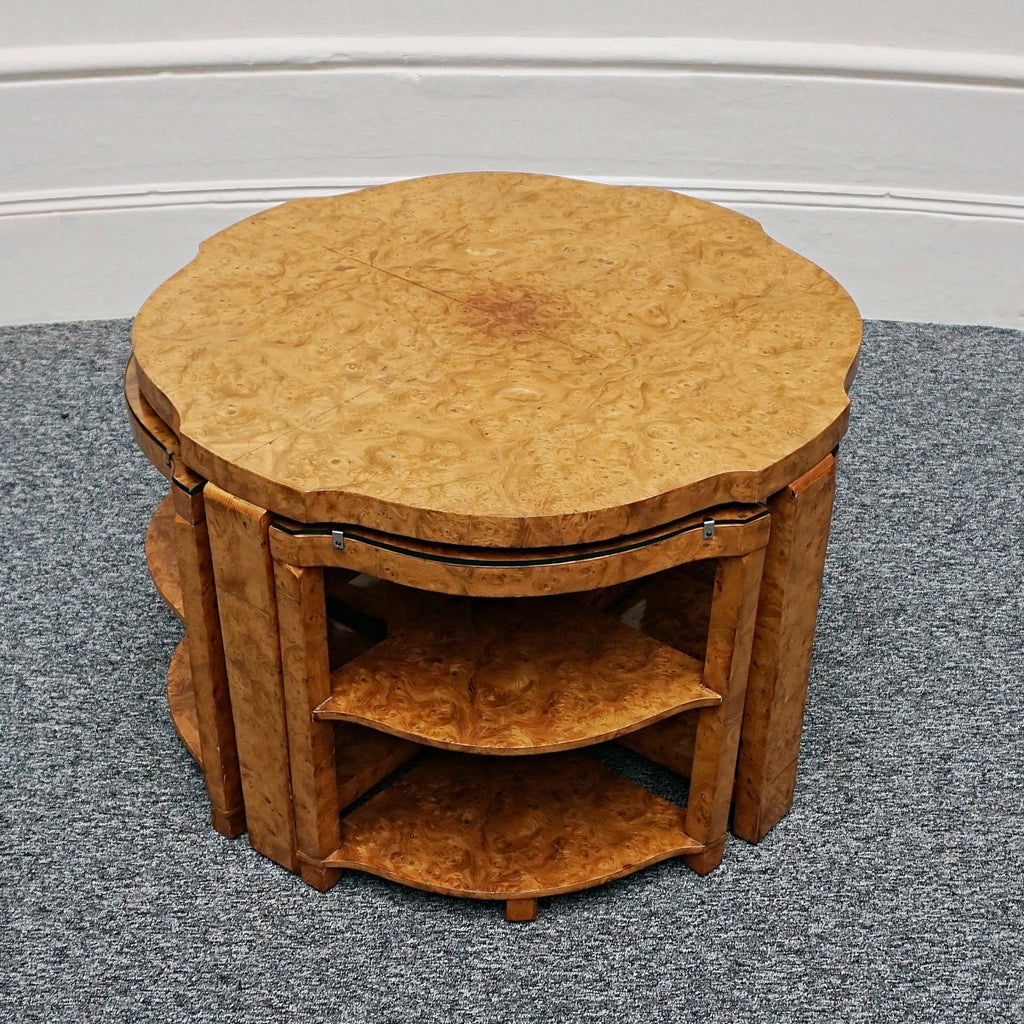 An Art Deco nest of tables by Harry & Lou Epstein Burr walnut veneered. Consisting of a central coffee table with four shelved pull out side tables. The tables have glass tops.