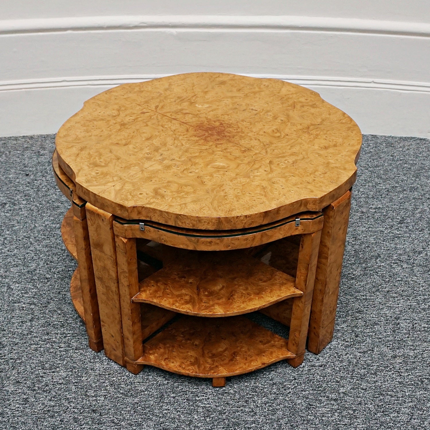 An Art Deco nest of tables by Harry & Lou Epstein Burr walnut veneered. Consisting of a central coffee table with four shelved pull out side tables. The tables have glass tops.