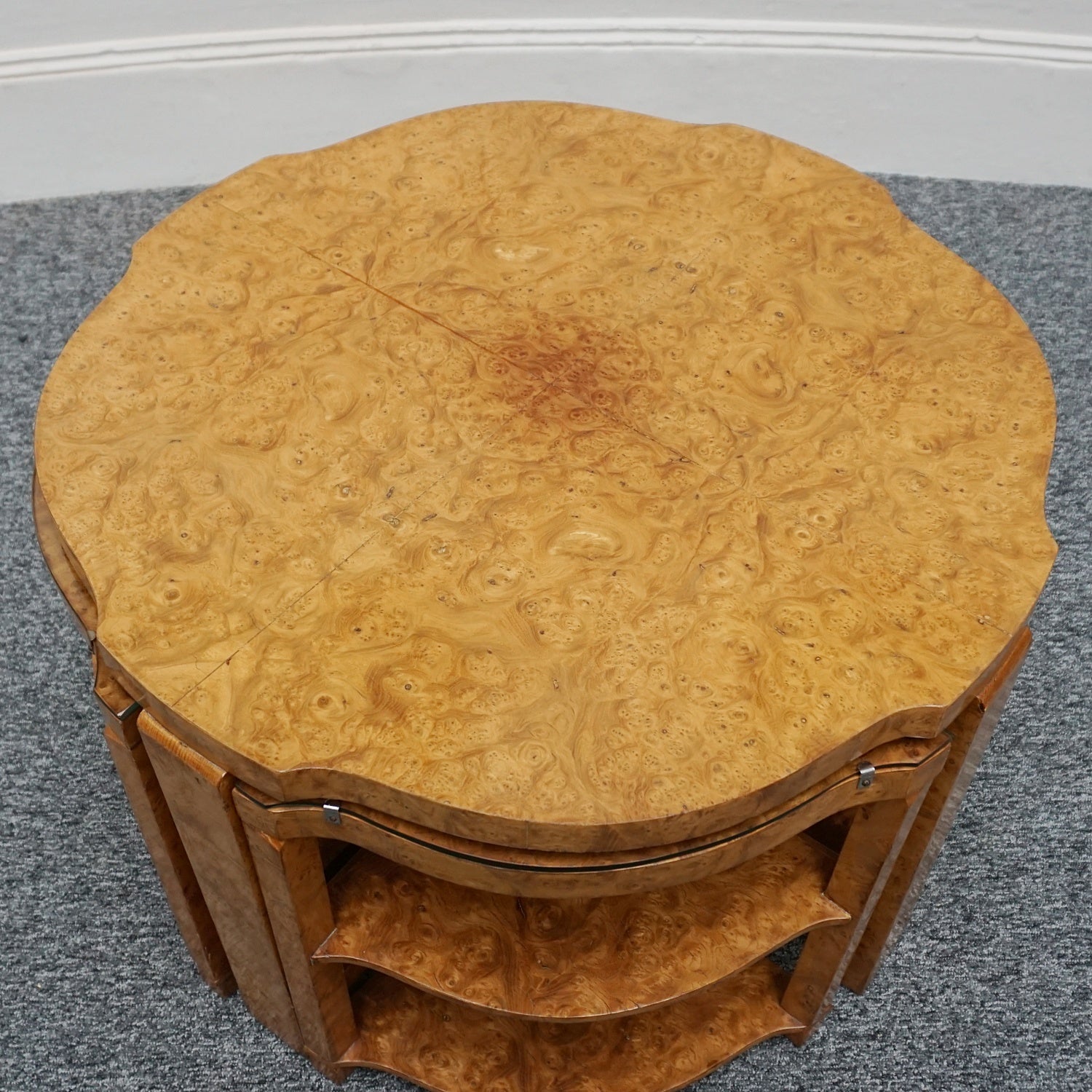 An Art Deco nest of tables by Harry & Lou Epstein Burr walnut veneered. Consisting of a central coffee table with four shelved pull out side tables. The tables have glass tops.