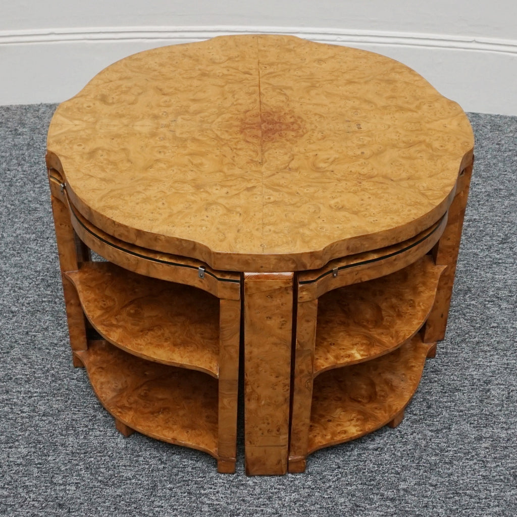 An Art Deco nest of tables by Harry & Lou Epstein Burr walnut veneered. Consisting of a central coffee table with four shelved pull out side tables. The tables have glass tops.