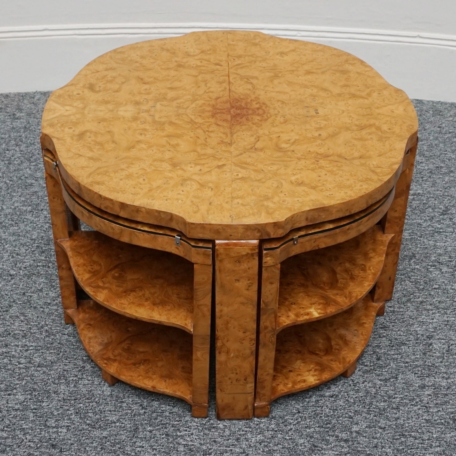 An Art Deco nest of tables by Harry & Lou Epstein Burr walnut veneered. Consisting of a central coffee table with four shelved pull out side tables. The tables have glass tops.