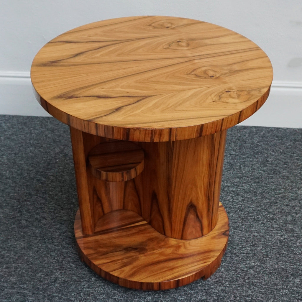 An Art Deco style centre table with a curved central column with hidden shelf to either side set over a circular base made from burr walnut veneer